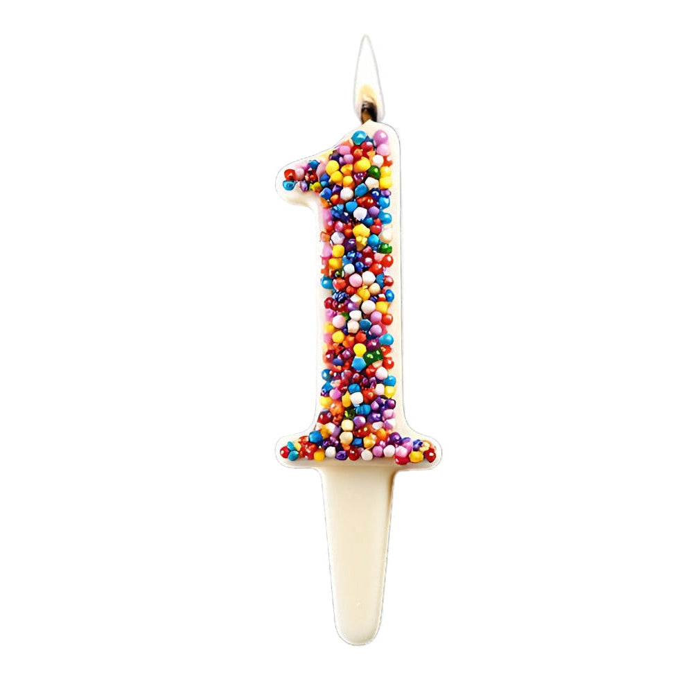 A patented flammable almond wick and white chocolate number candle with the number 1 adorned with colorful rainbow nonpareils, designed for use as a birthday or celebration candle.